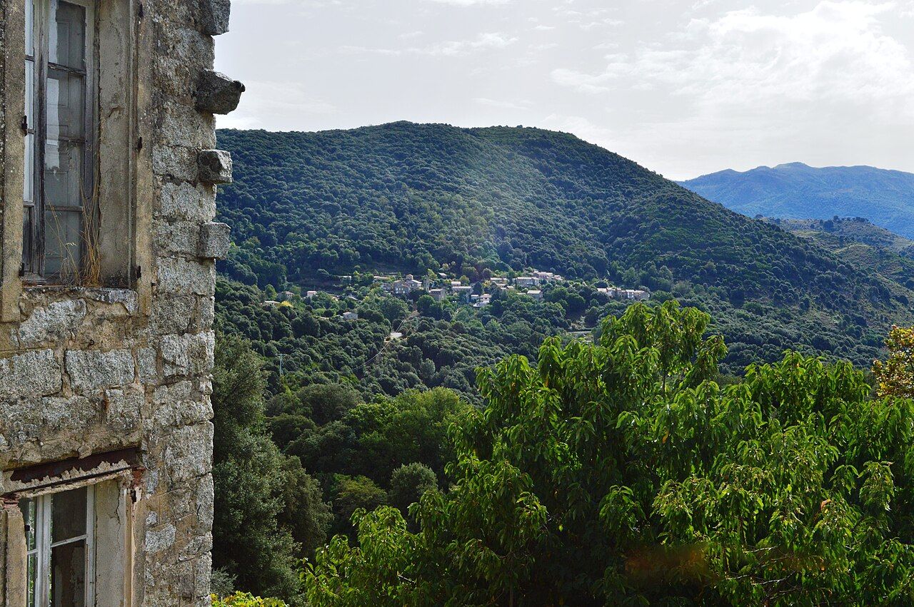 Le village d'Azilone accroché au flanc d'une colline boisée, vu depuis Ampaza de l'autre côté de la vallée