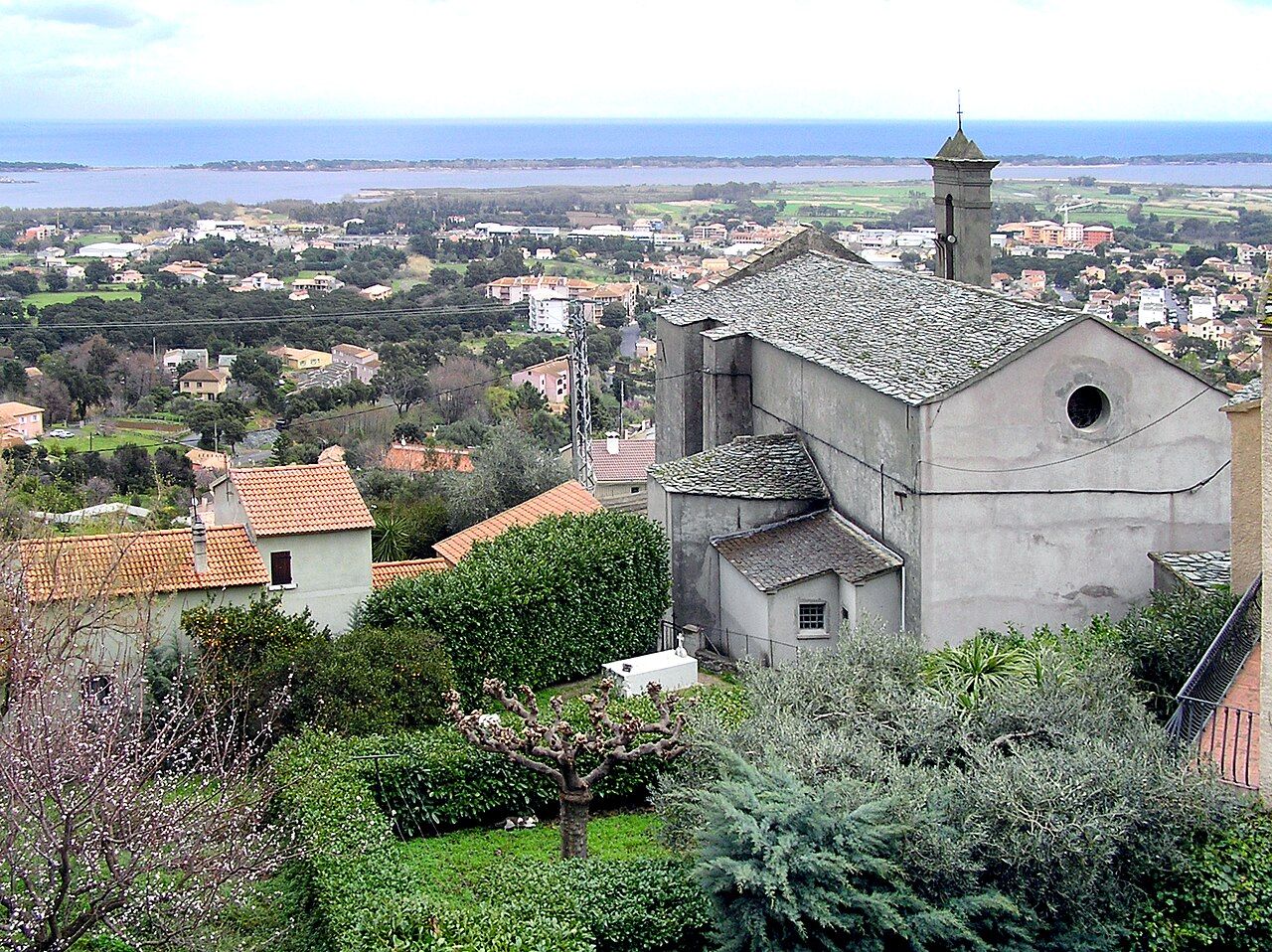 L'église Saint-André de Biguglia, au toit de lauzes, dominant les maisons de la plaine, l'étang de Biguglia et la mer