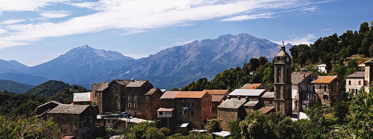 Panorama de Bustanico, ses maisons de pierre et le clocher de l’église Saint-Césaire, avec au loin le Monte d’Oru et le Monte Cardu