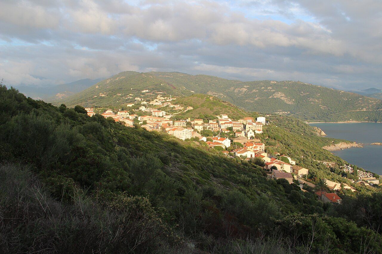 Le village de Cargèse étagé sur une colline couverte de maquis, au-dessus de la mer, à la lumière du soir