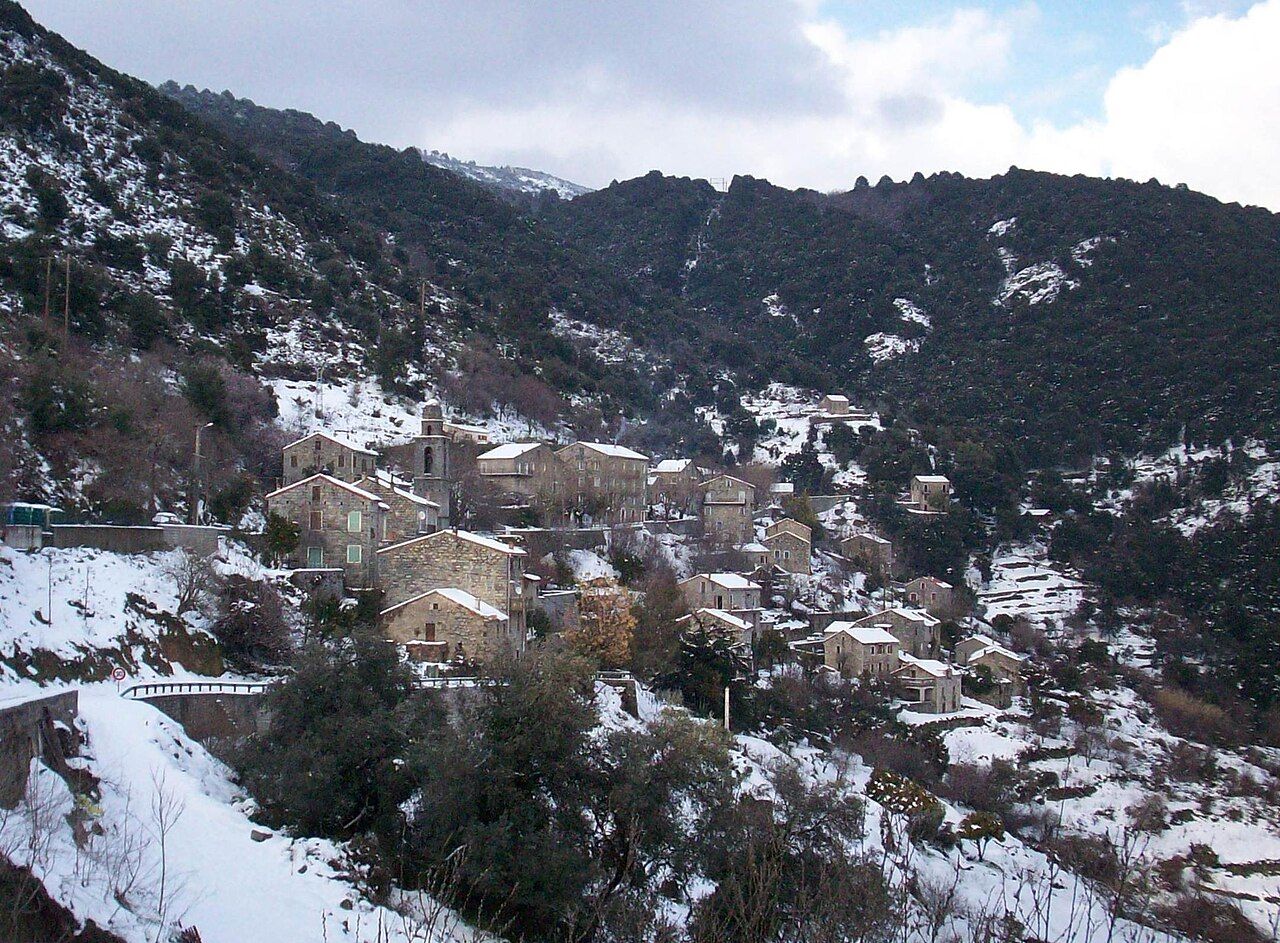 Le village de Cargiaca sous la neige, ses maisons de granite étagées sur la pente et le clocher de l’église Saint-Paul, au pied des montagnes boisées