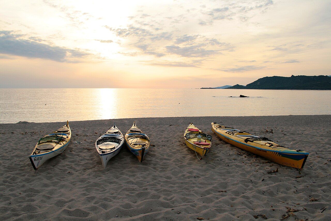 Kayaks de mer posés sur la plage de Tiuccia, à Casaglione, au soleil couchant sur le golfe de Sagone