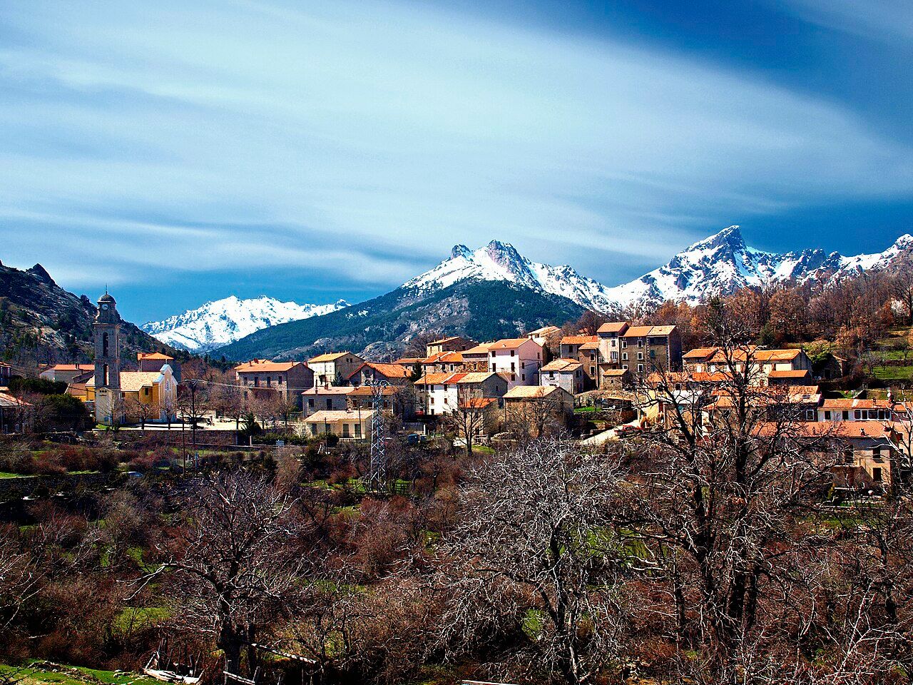 Le village de Casamaccioli, son clocher et ses maisons aux toits orangés, devant les sommets enneigés du Niolu dont la Paglia Orba