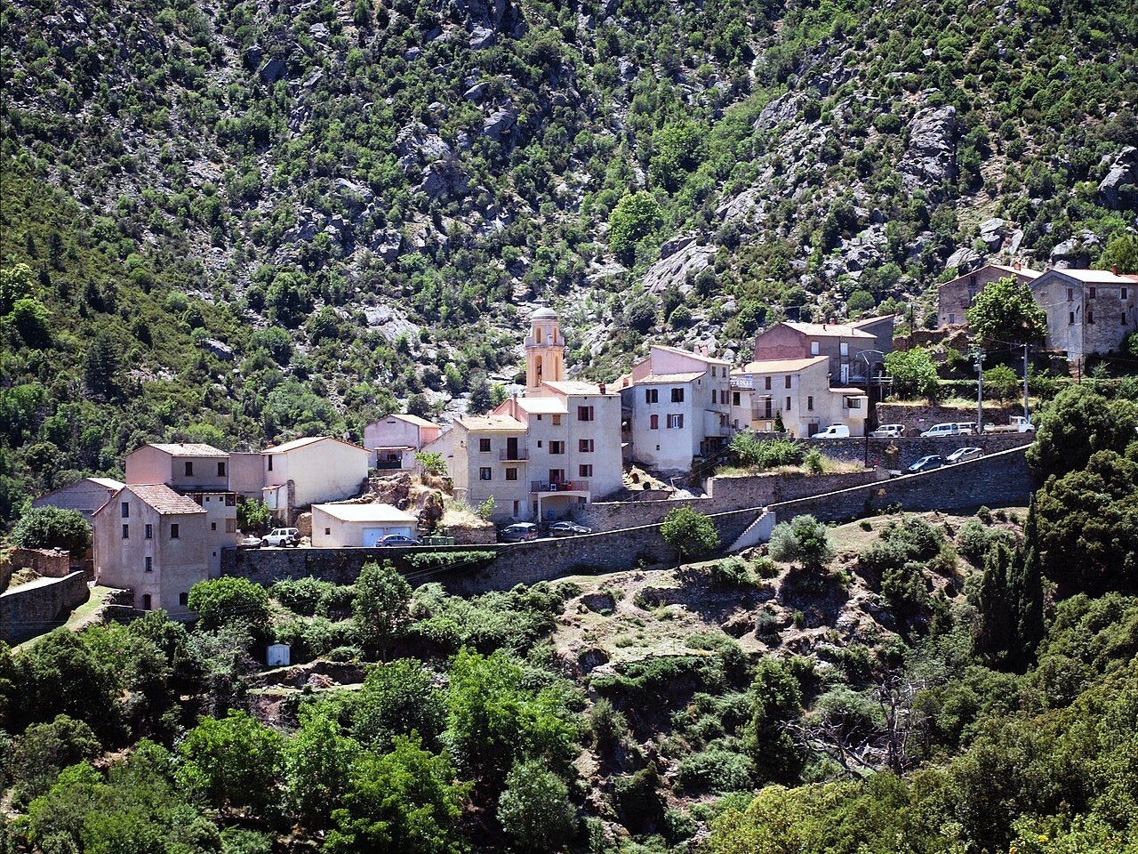 Le village de Castiglione, maisons claires et clocher alignés le long de la route, au pied d’un versant rocheux couvert de maquis