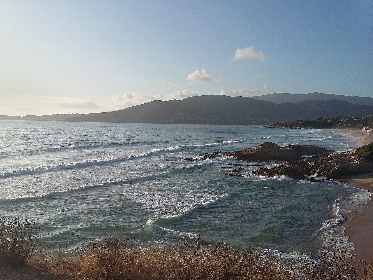 Le rivage rocheux et la plage d’Esigna, sur la côte de Coggia, face au golfe de Sagone et aux montagnes