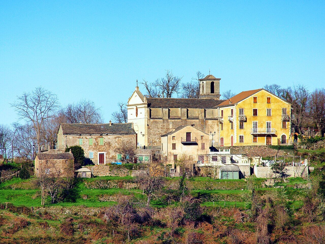 L’église paroissiale Saint-Césaire de Croce et son clocher, entourés de maisons, au-dessus de terrasses vertes