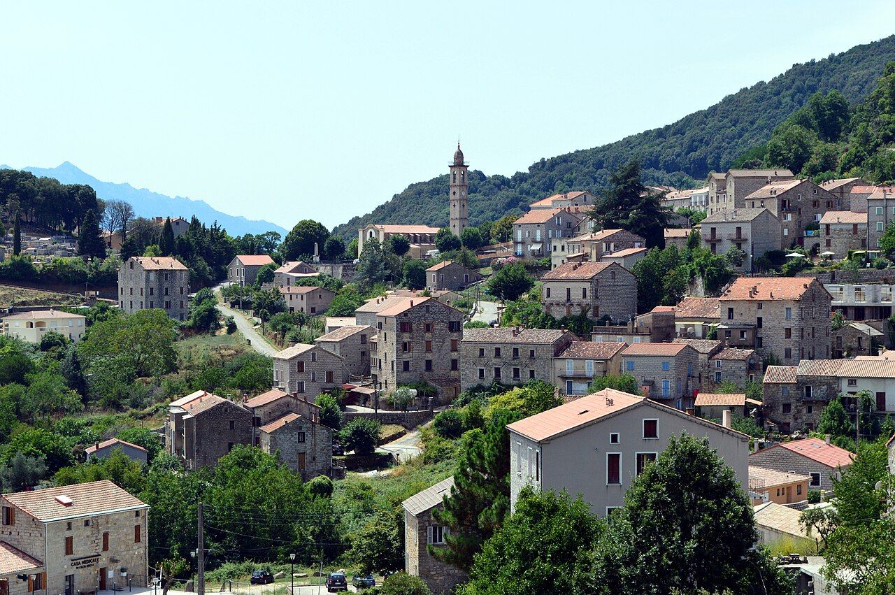 Vue générale de Levie : maisons de pierre étagées sur la pente, clocher et collines boisées