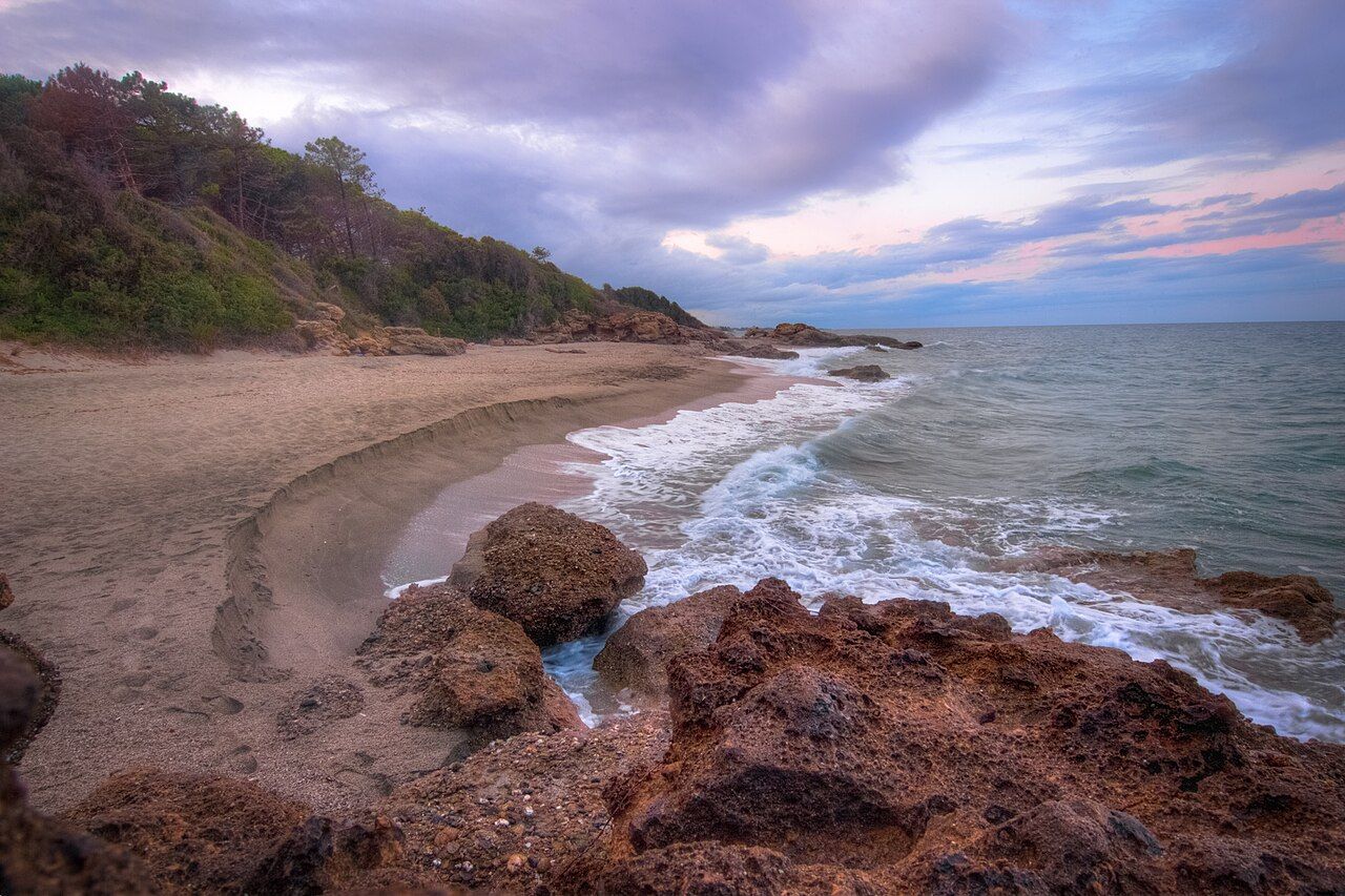 Plage de sable et rochers ocre à la marine de Bravone, sur le littoral de Linguizzetta, au crépuscule