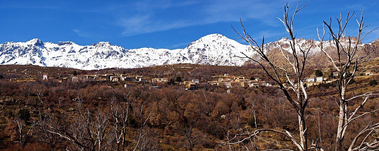 Le village de Lozzi au milieu des châtaigniers, sous la crête enneigée du massif du Monte Cinto