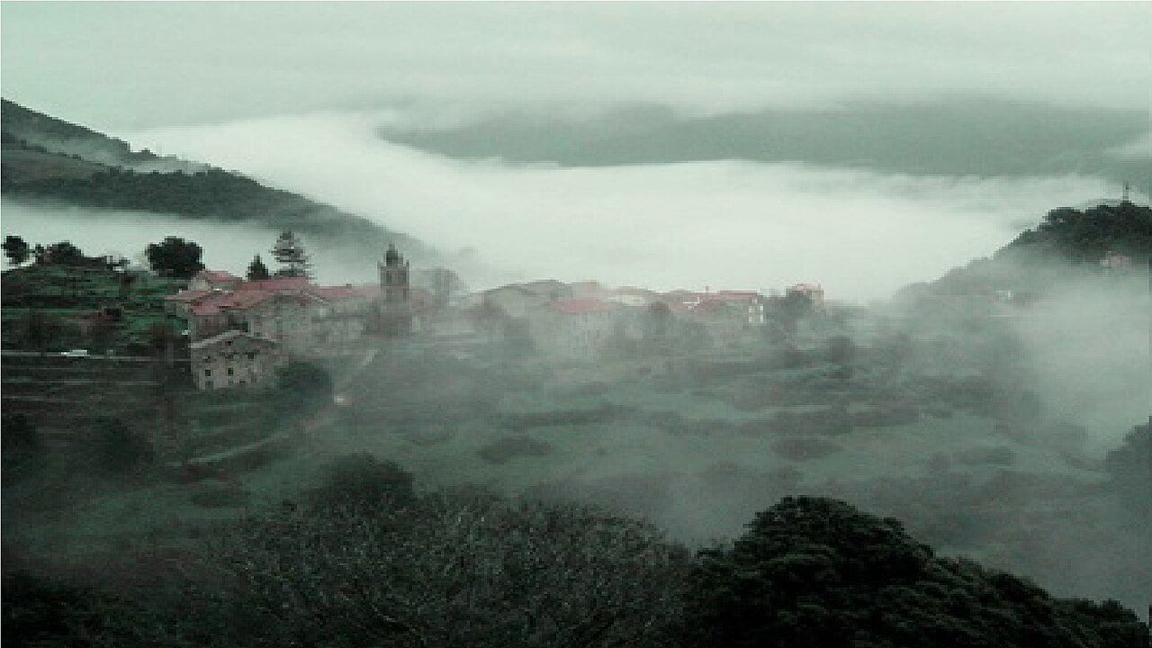 Le village de Mela sur sa crête, ses toits de tuiles et son clocher émergeant de la brume qui remplit la vallée du Fiumicicoli