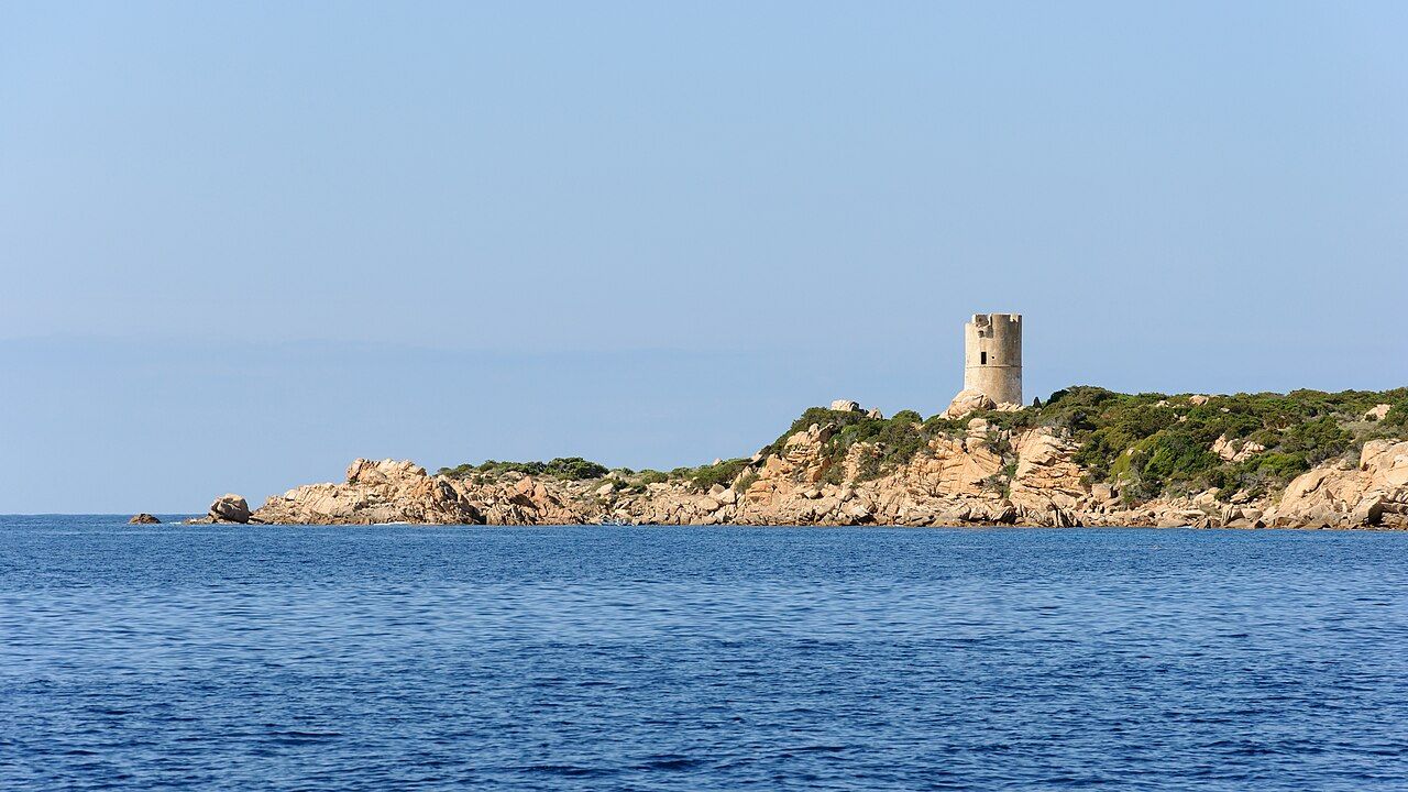 La tour génoise d’Olmeto, vue de la mer, sur une pointe de rochers de granite couverte de maquis, sur la côte de Monacia-d’Aullène