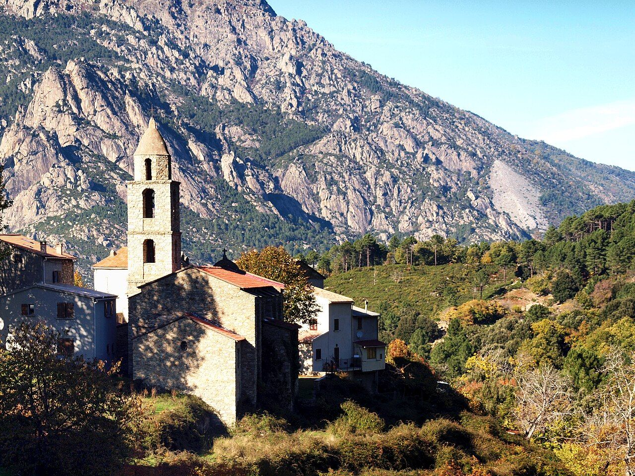 L’église de l’Assomption de Muracciole et son clocher en pierre, devant les falaises rocheuses du Razzo Bianco, sur le territoire de Venaco
