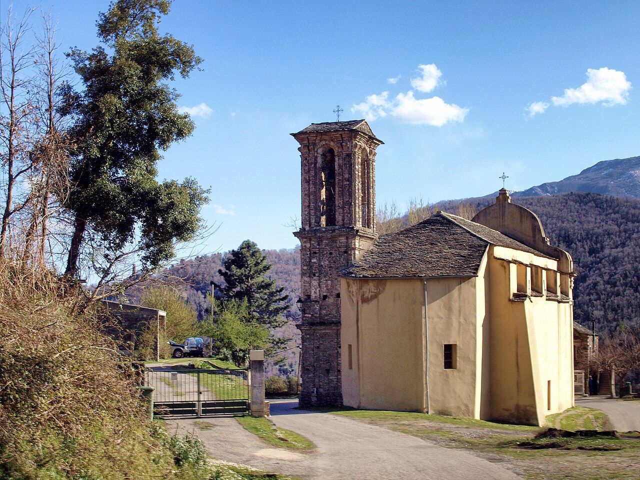 L’église paroissiale Saint-Michel de Nocario et son campanile de pierre, au milieu des arbres