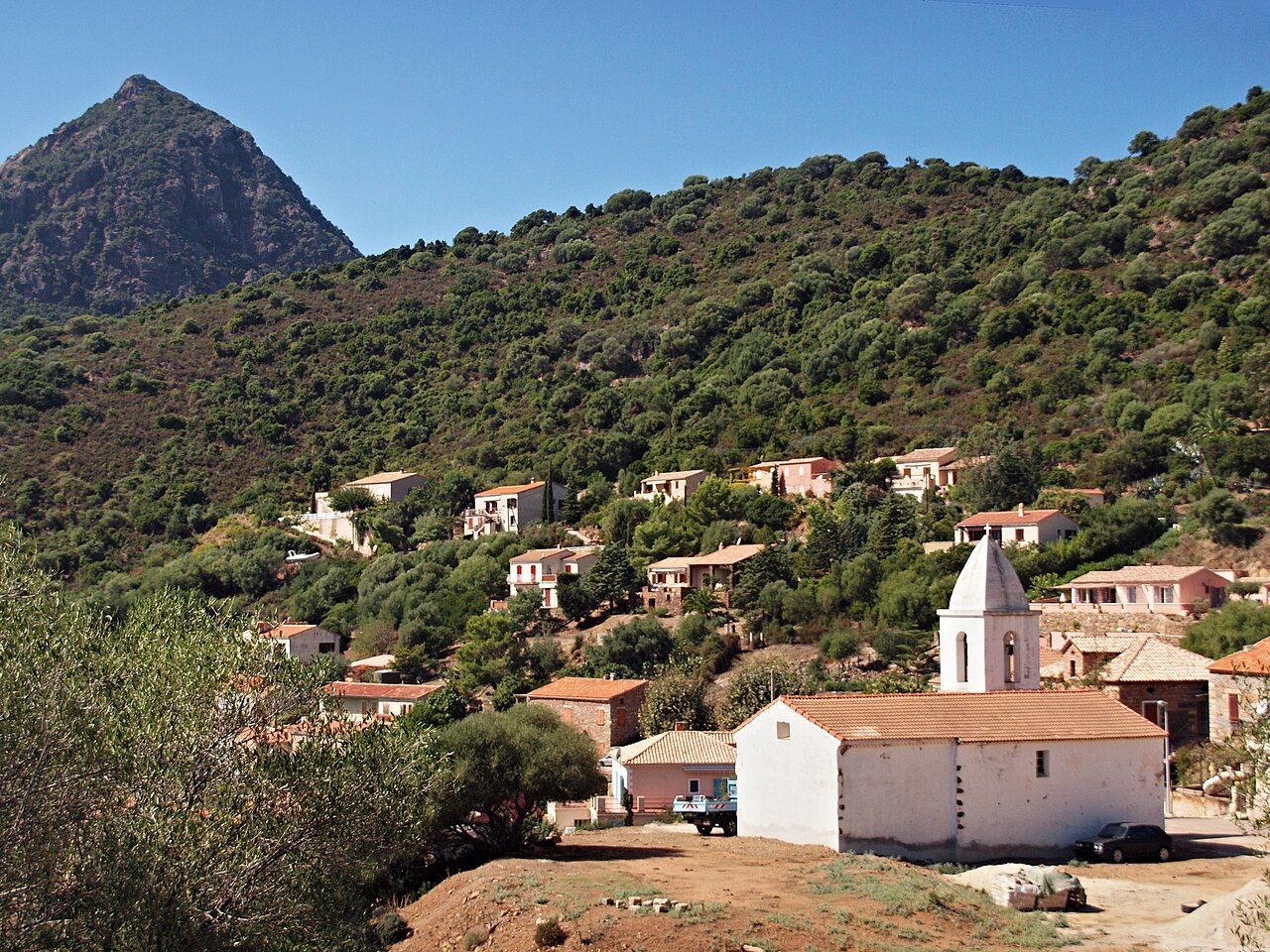 Le village d’Osani, son église blanche à clocher et ses maisons sur une colline de maquis, dominés par un pic rocheux