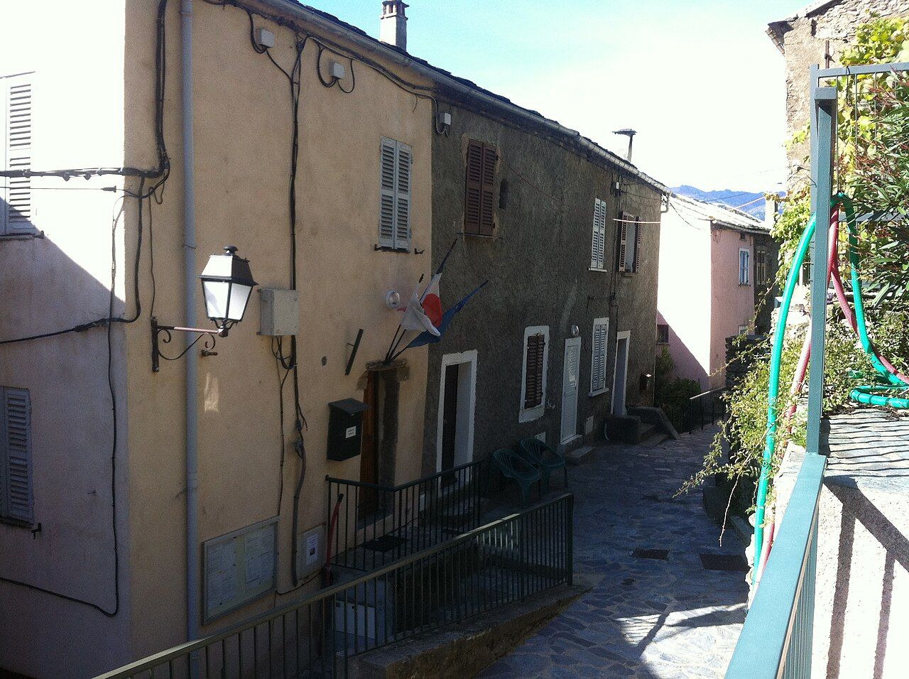 La mairie de Parata et ses drapeaux, dans une ruelle pavée du village bordée de maisons