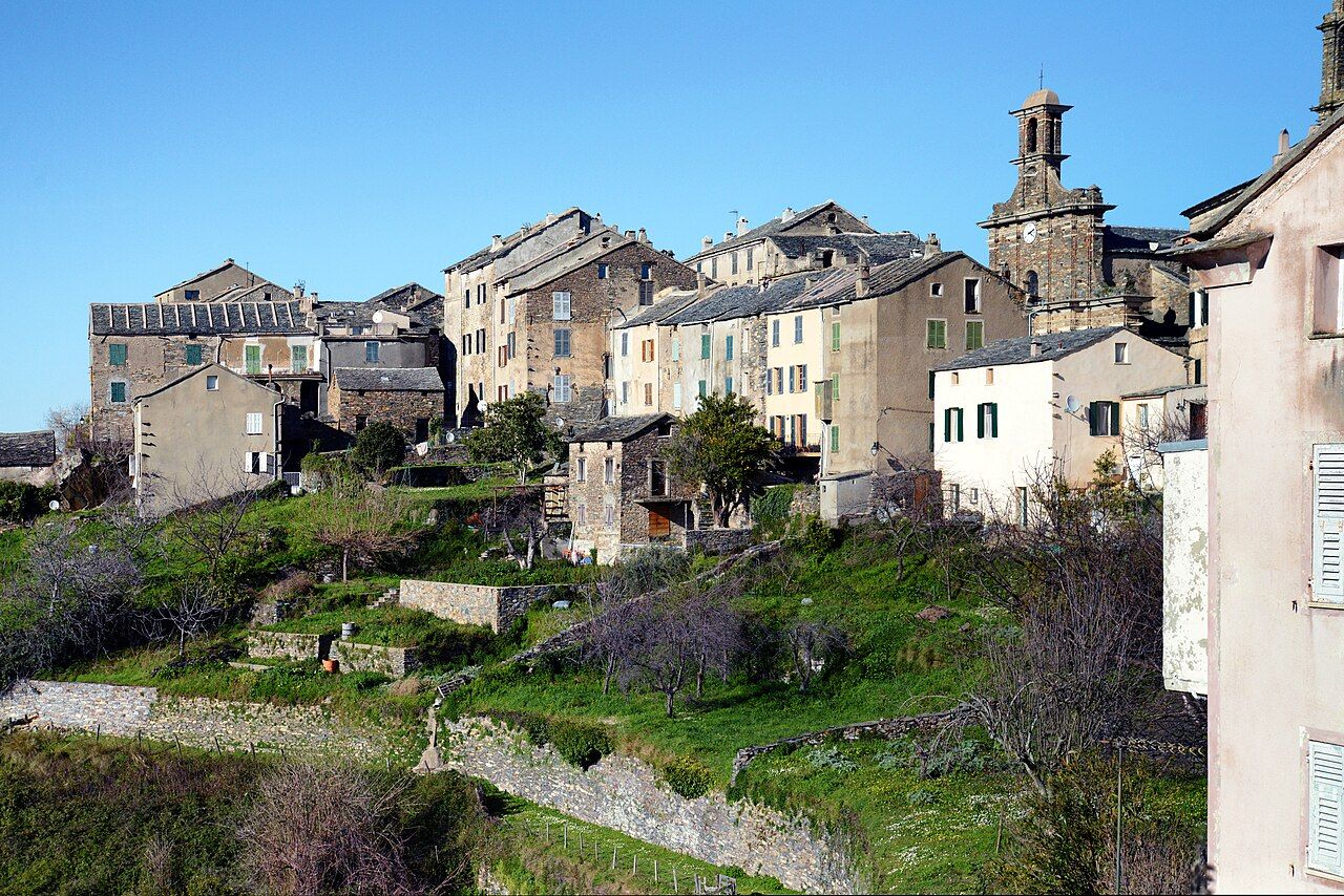 Le village perché de Penta-di-Casinca, ses hautes maisons de pierre et le clocher de l’église San Michele au-dessus de terrasses vertes