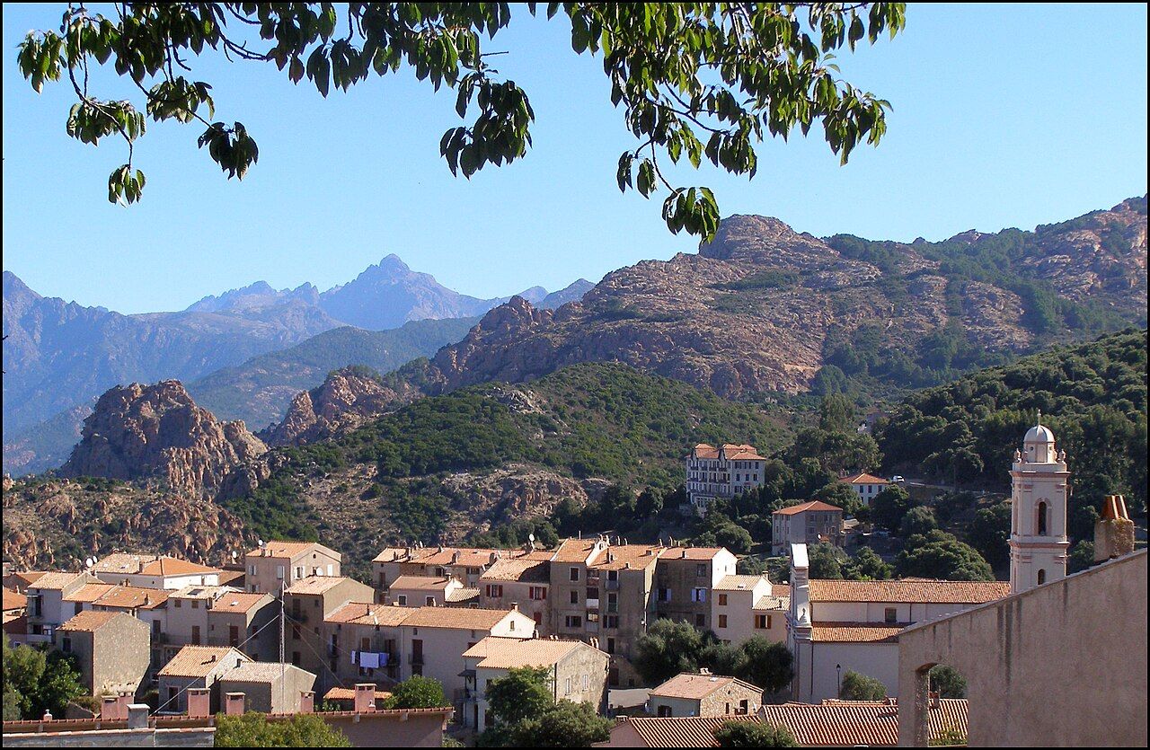 Les maisons de Piana et le clocher de l'église, devant les reliefs de granit rouge et les montagnes