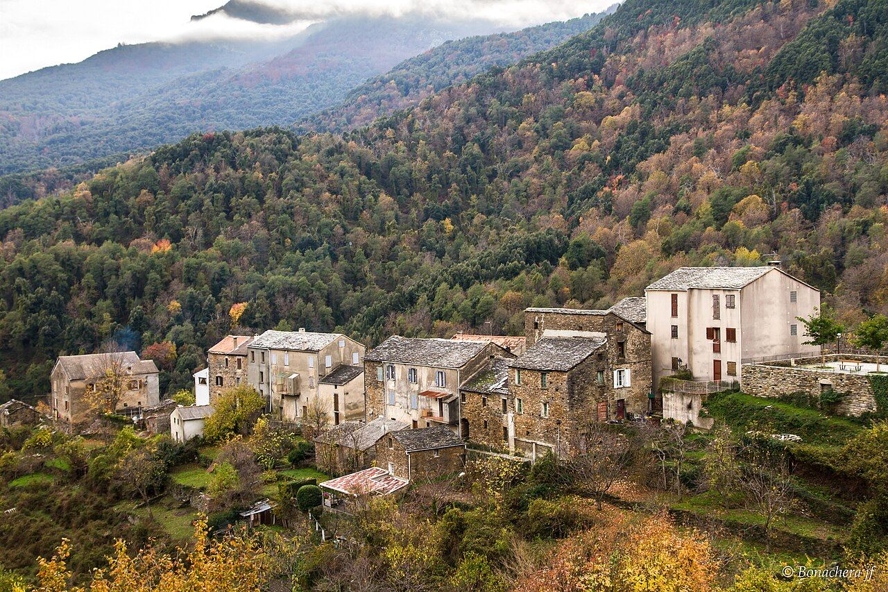 Les maisons de pierre aux toits d’ardoise de Pie-d’Orezza, devant un versant boisé aux couleurs d’automne