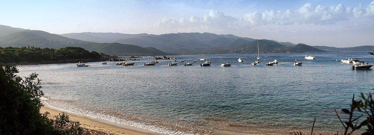 L'anse de Medea, au sud de la presqu'île de l'Isolella : plage de sable, bateaux au mouillage et collines boisées
