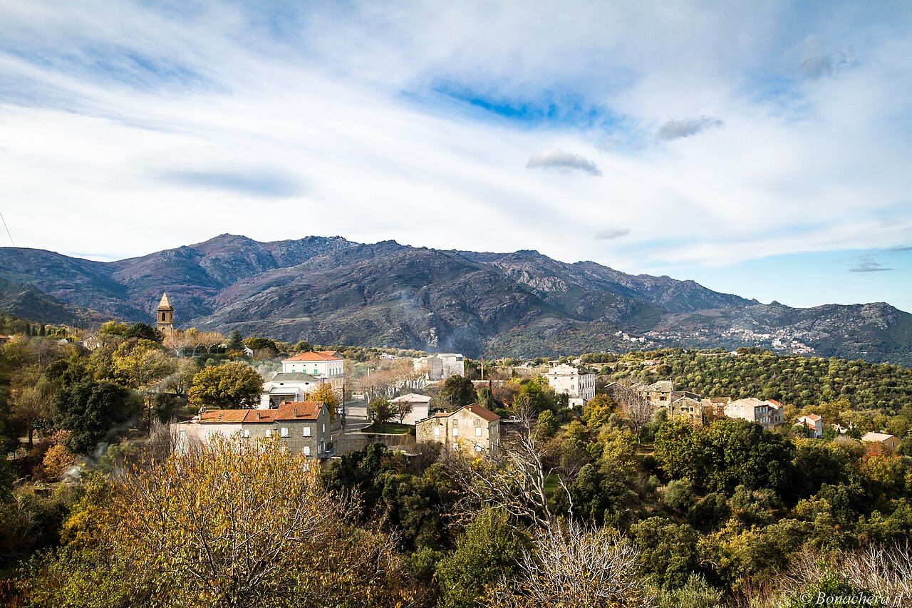 Le village de Rapale, son clocher et ses maisons au milieu des arbres, avec les montagnes du Nebbio en arrière-plan
