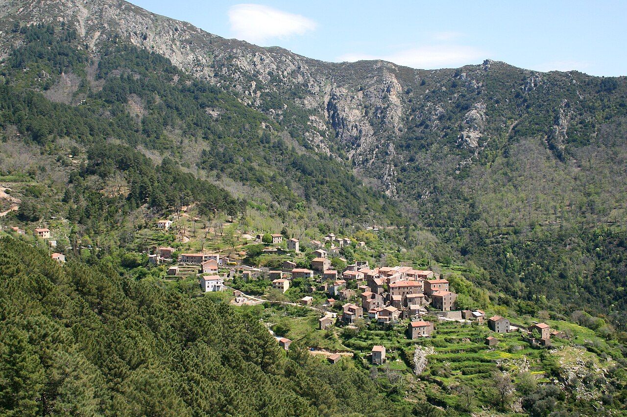 Le village de Rosazia, maisons de pierre serrées sur un promontoire en terrasses, au pied d’une montagne boisée et rocheuse
