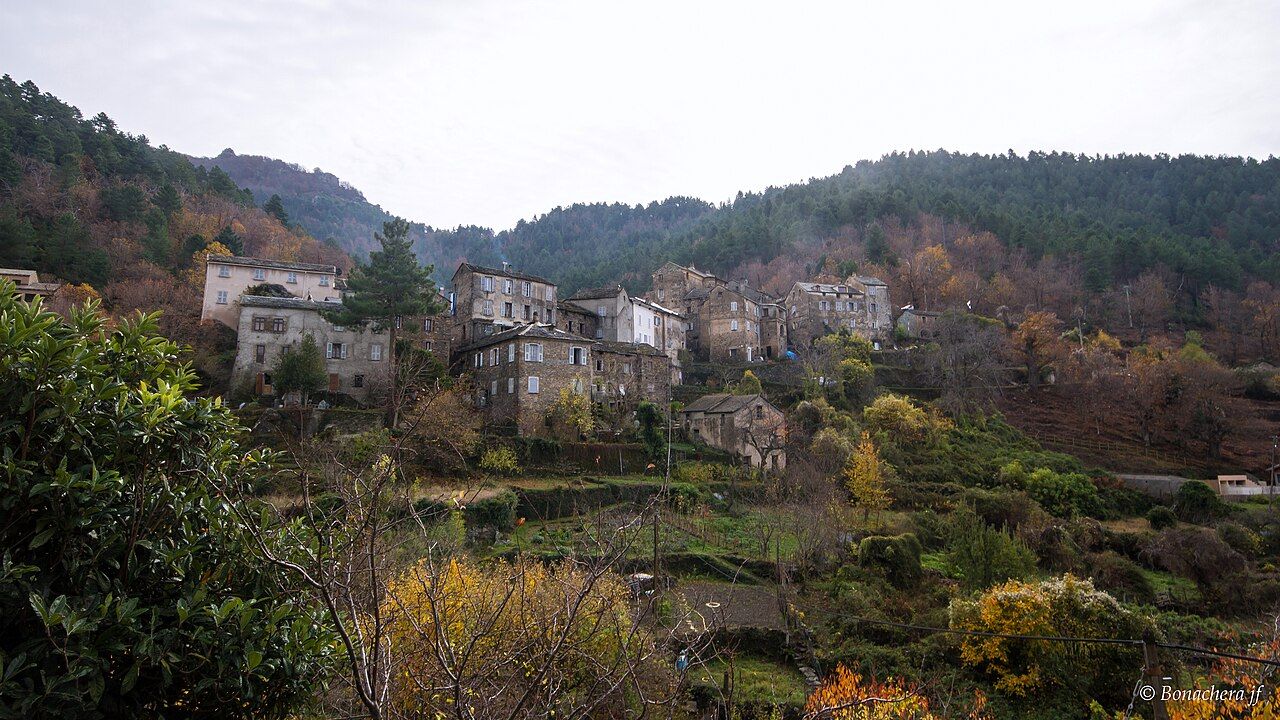 Le village de Saliceto en automne, hautes maisons de pierre au fond d’une vallée boisée, vu depuis la route de Gavignano