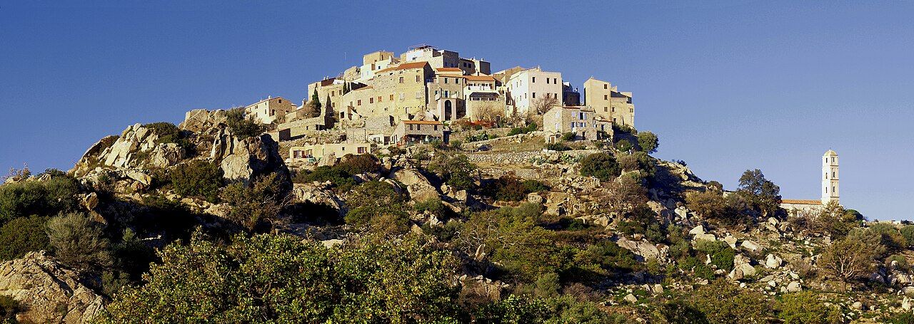 Le village de Sant'Antonino serré au sommet d'une colline de rochers de granit, avec le clocher blanc de l'église en contrebas à droite