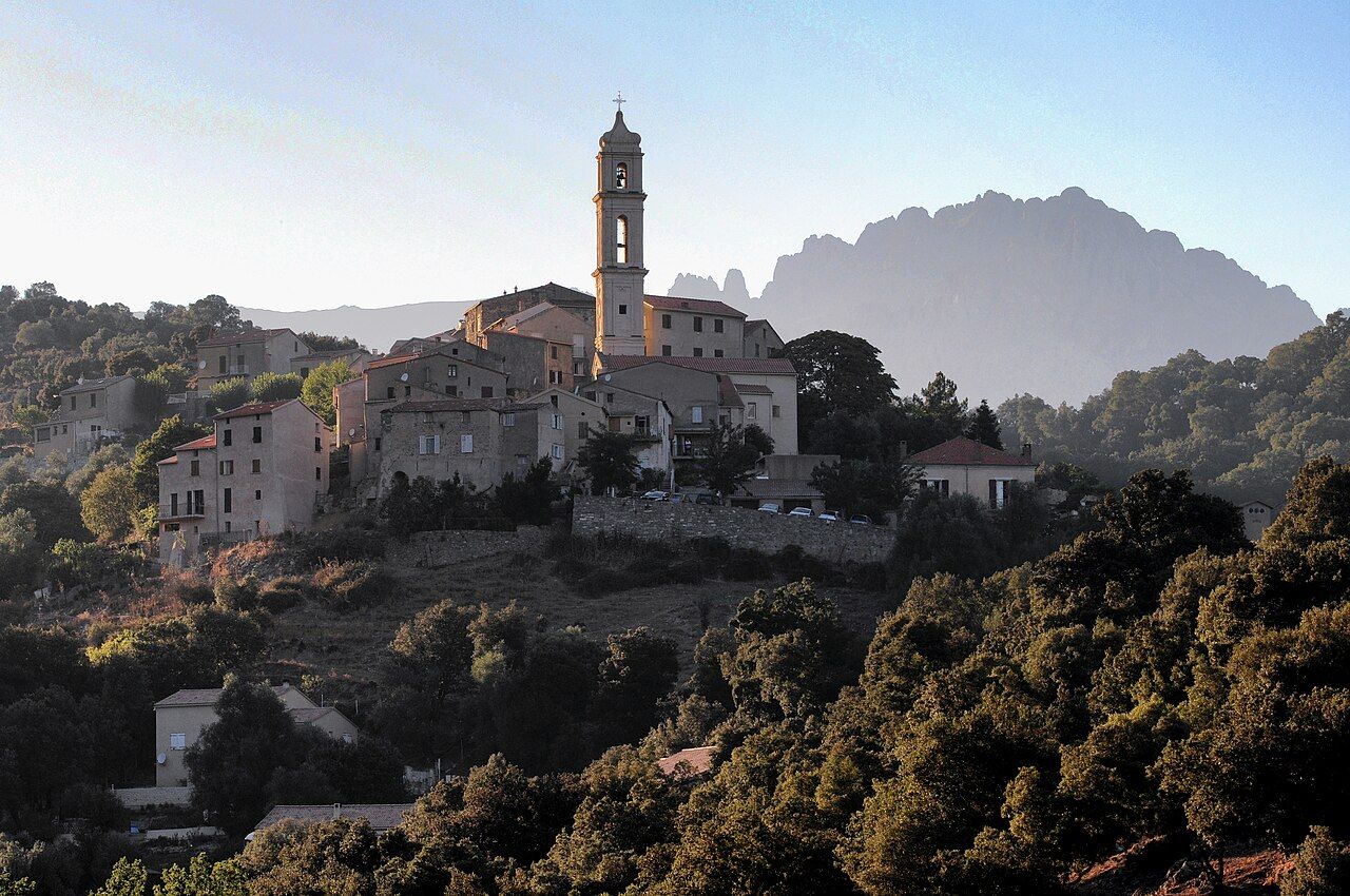 Le village de Soveria, ses maisons de pierre et le haut clocher de son église, avec la silhouette des aiguilles de Popolasca à l’arrière-plan