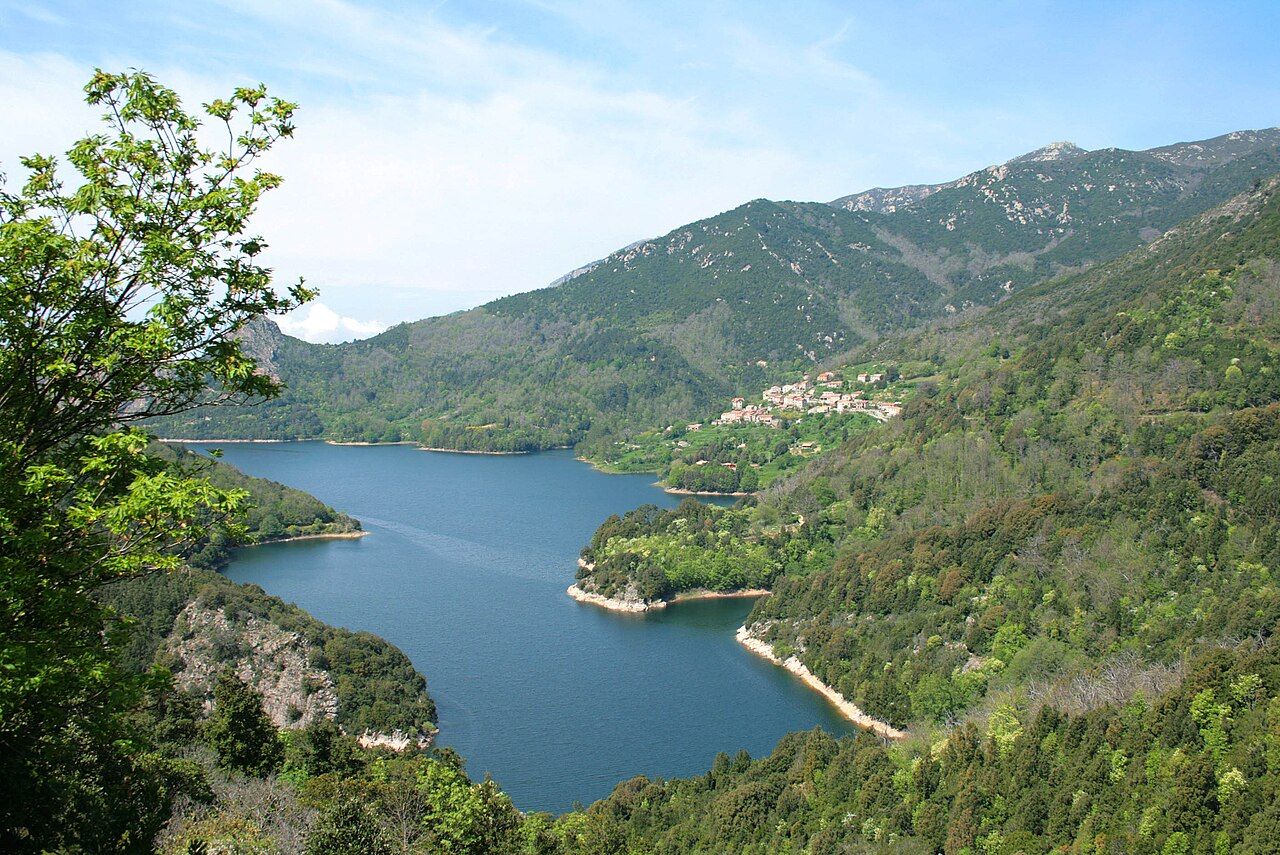 Le village de Tolla, sur une pente boisée, au-dessus des eaux bleues du lac de Tolla, entouré de montagnes
