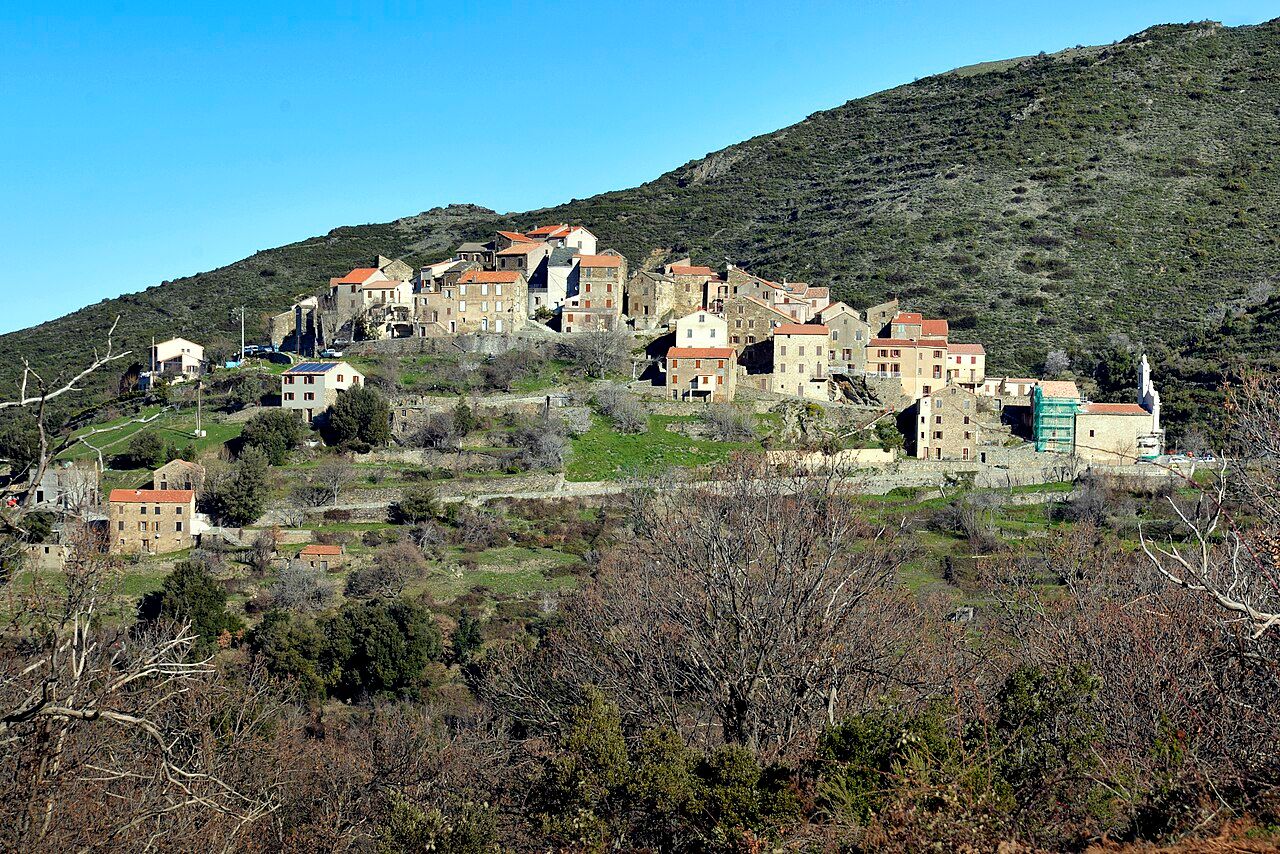 Le village de Tralonca, maisons de pierre serrées sur une crête au pied d’une colline couverte d’anciennes terrasses, vu depuis le cimetière