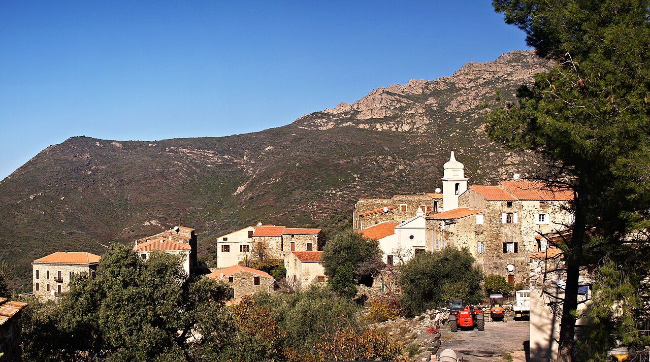 Les maisons en pierre d’Urtaca et le clocher blanc de l’église, au pied d’un versant de maquis dominé par des crêtes rocheuses