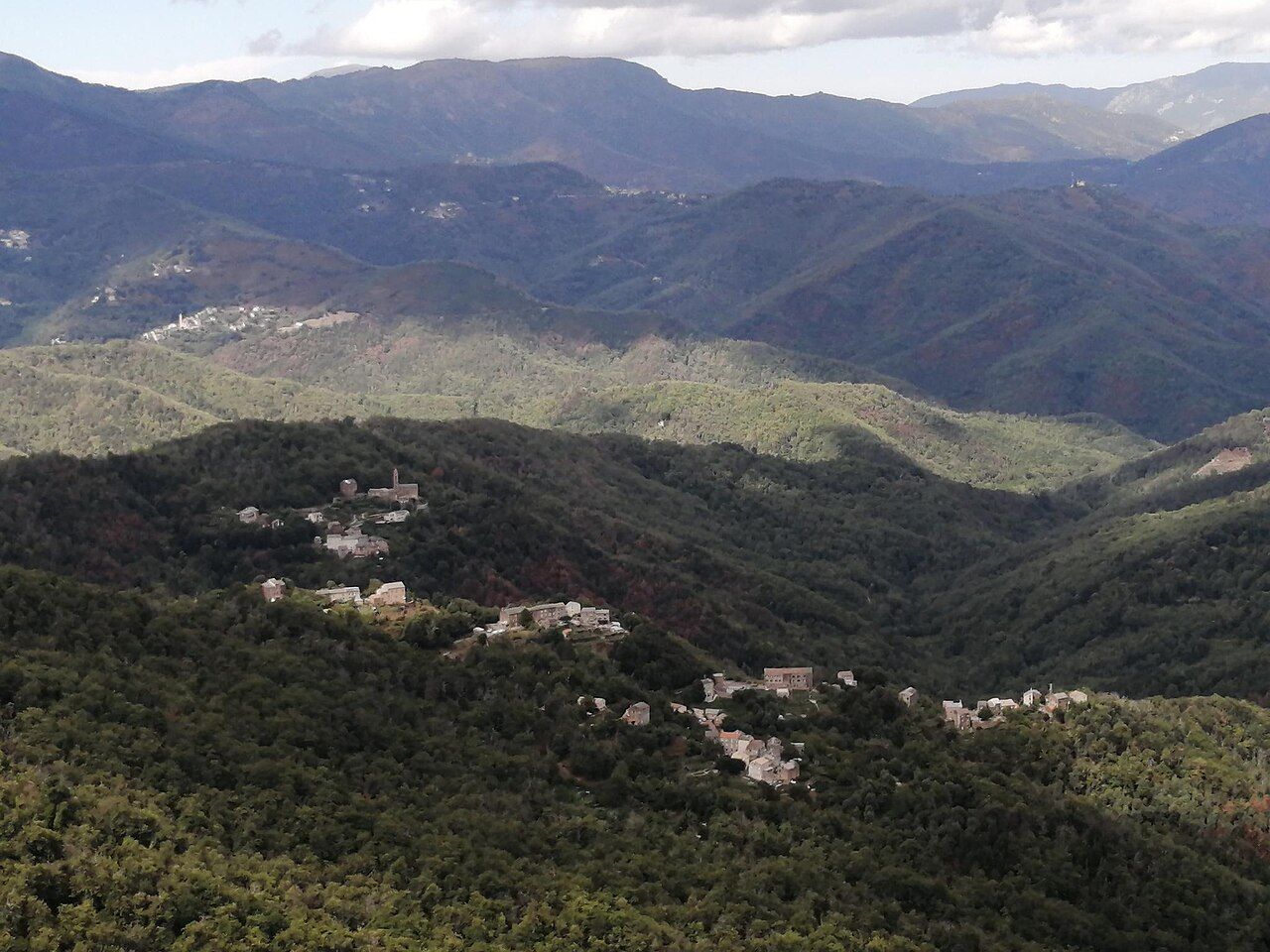 Les hameaux de Valle-d’Orezza étagés dans la forêt, avec Rapaggio en arrière-plan à gauche, vus depuis le Monte Zuccarello