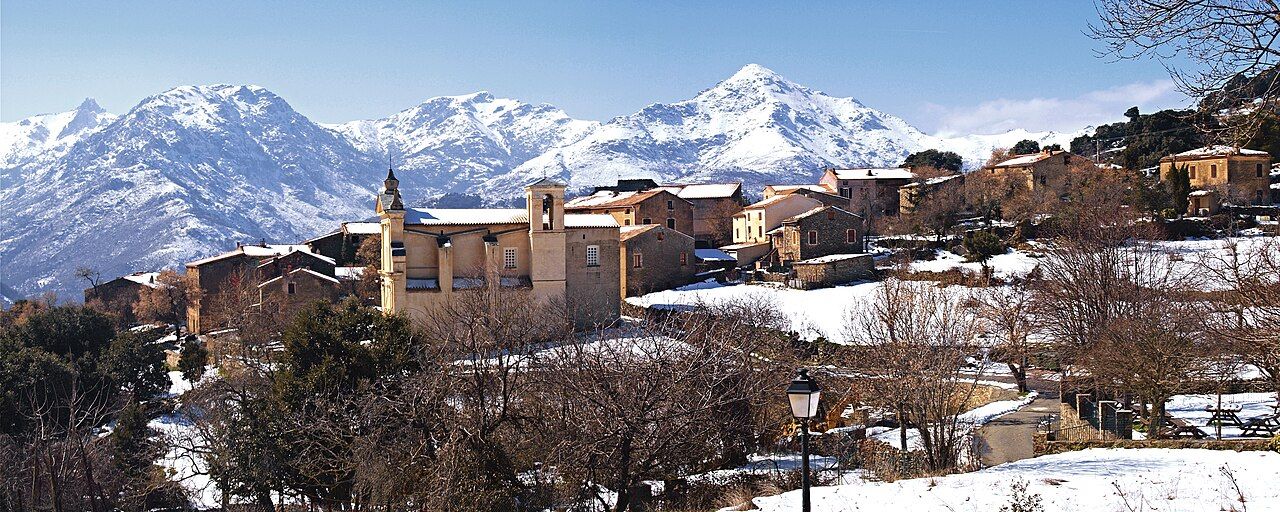 Le village de Vallica sous la neige, avec l’église de la Nativité et les sommets enneigés du cirque de la Tartagine en arrière-plan