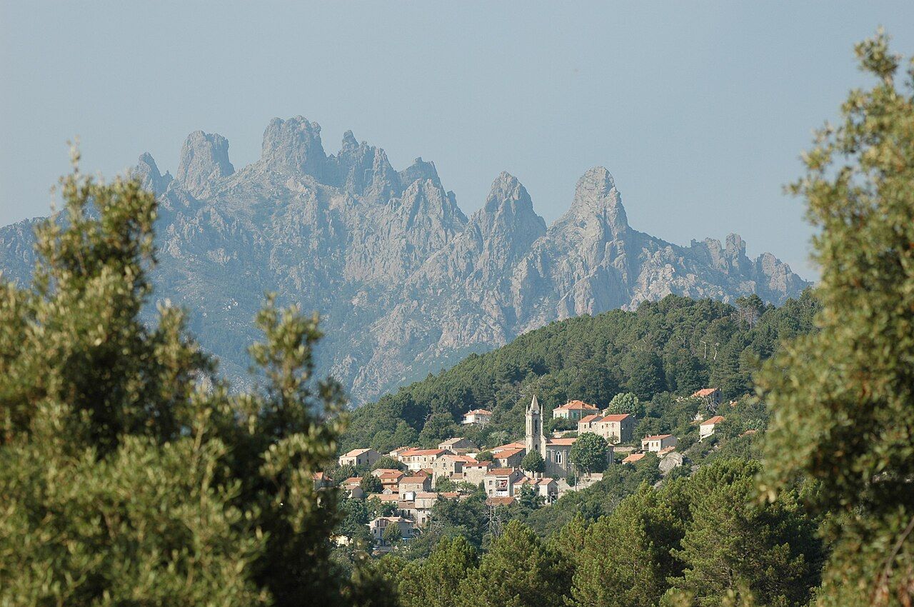 Le village de Zonza entouré de forêts, avec les aiguilles de Bavella en arrière-plan
